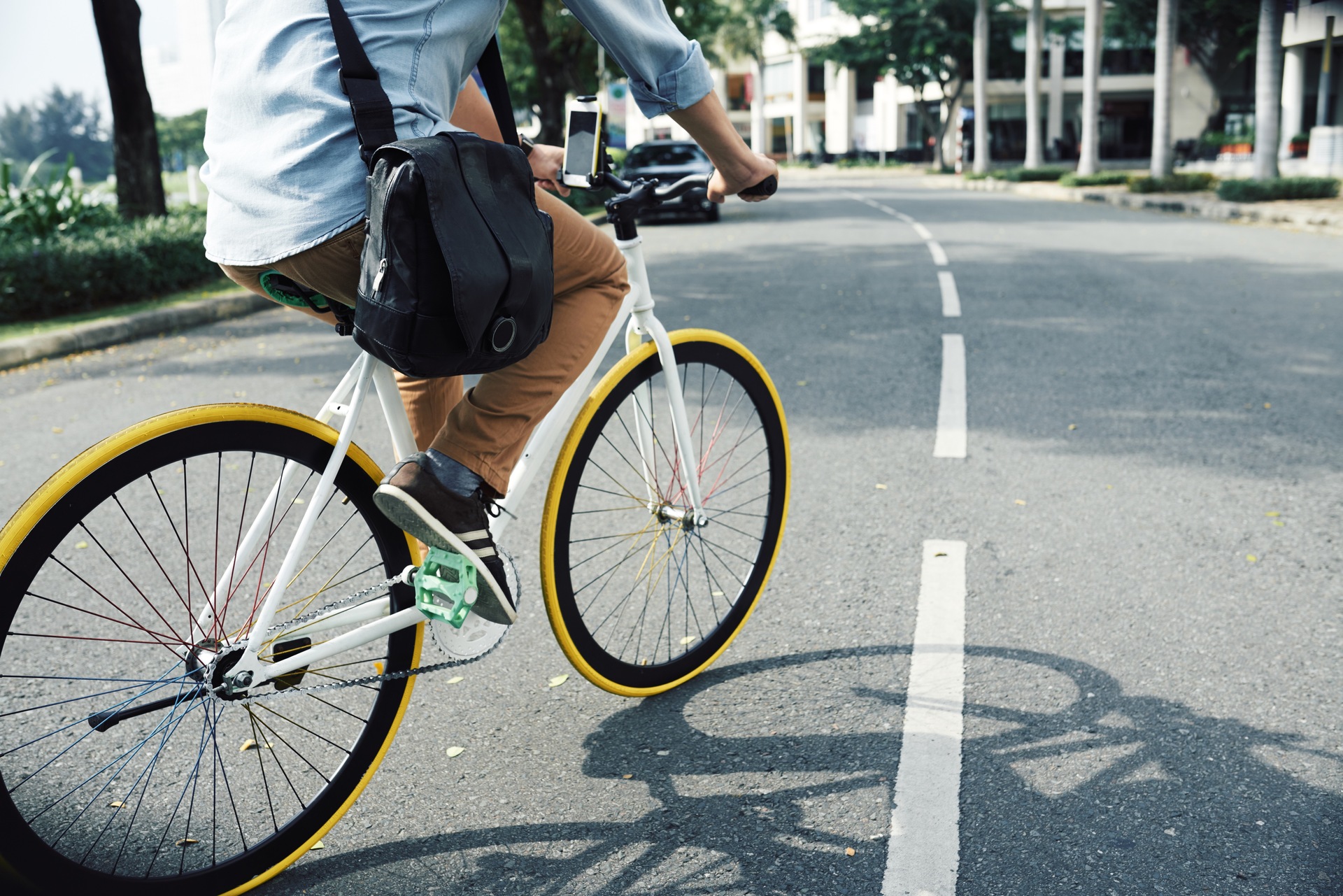 Een fietsende man midden op de weg. De fiets heeft geel gekleurde banden en regenboog spaken.